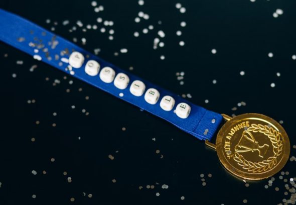 Close-up of a gold medal on a blue ribbon with 'possible' beading, symbolizing achievement.